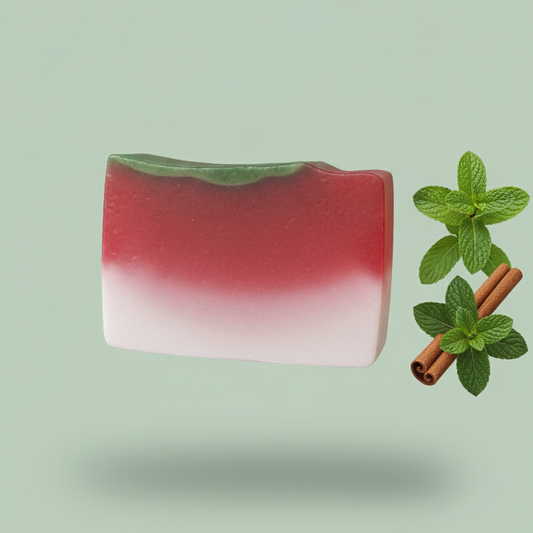 Red and white soap bar with mint leaves and a cinnamon stick on a light green background