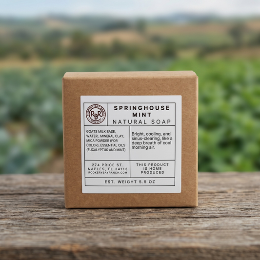 Box of Springhouse Mint natural soap on a wooden surface with a blurred green field background